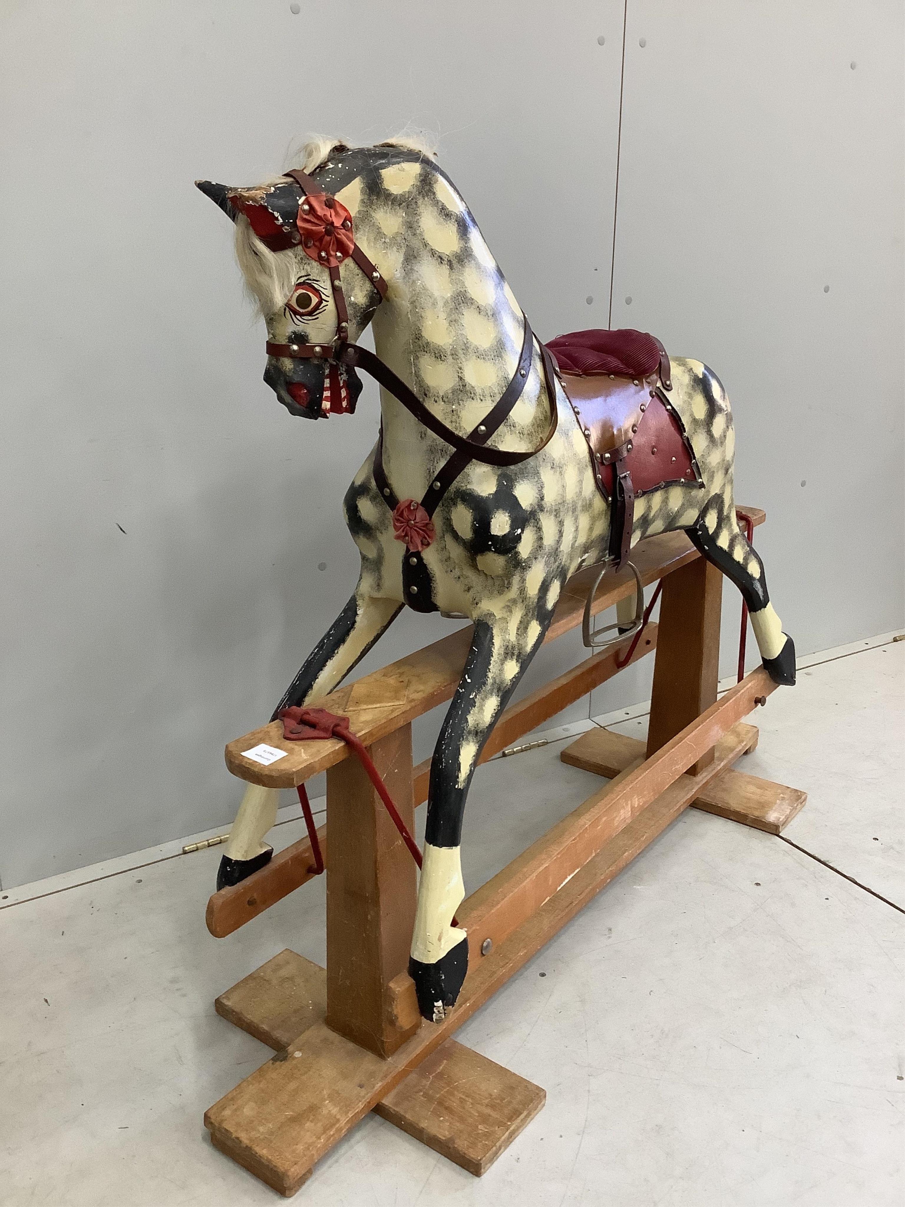 A mid-20th century dapple grey rocking horse, probably by Collinson, with corduroy and leather saddle and painted wooden body, 112cm high, the stand 137cm long. Condition fair, losses to the paint work and notable damage